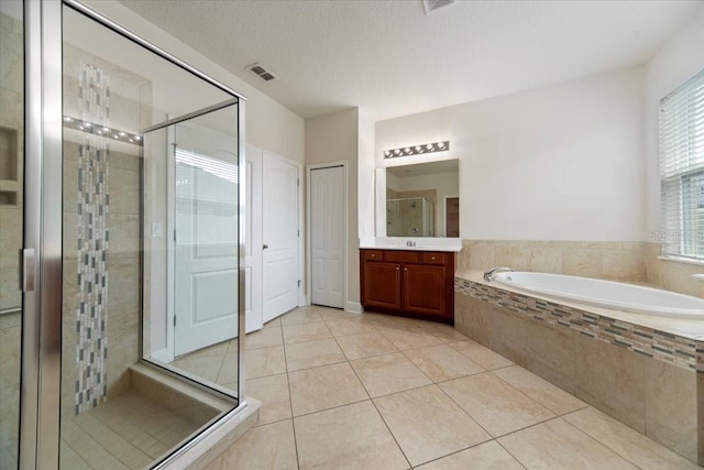 bathroom with a textured ceiling, shower with separate bathtub, vanity, and tile patterned floors