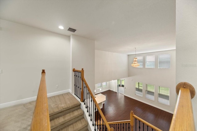 stairs with carpet flooring and a chandelier