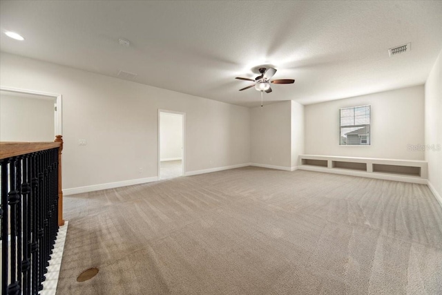 unfurnished living room with a textured ceiling, light carpet, ceiling fan, and a brick fireplace