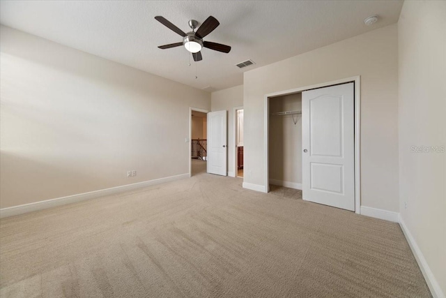 unfurnished bedroom with ceiling fan, light colored carpet, and a closet