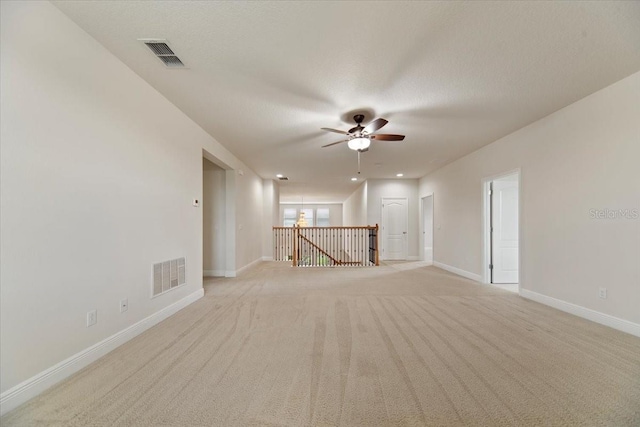 unfurnished living room with ceiling fan, light colored carpet, and a textured ceiling