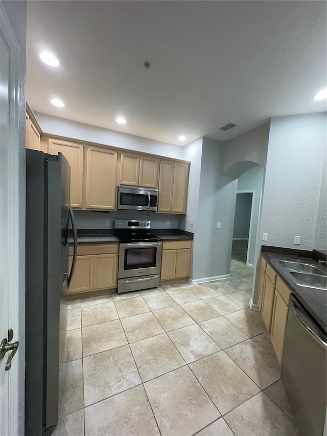 kitchen with light brown cabinets, sink, light tile patterned floors, and stainless steel appliances