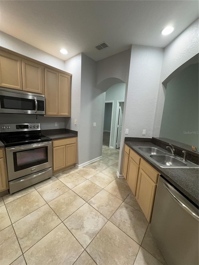 kitchen with light tile patterned floors, appliances with stainless steel finishes, and sink