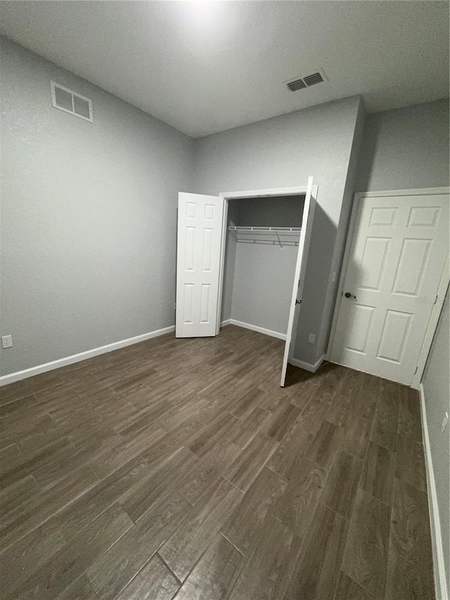 unfurnished bedroom with a closet and dark hardwood / wood-style flooring