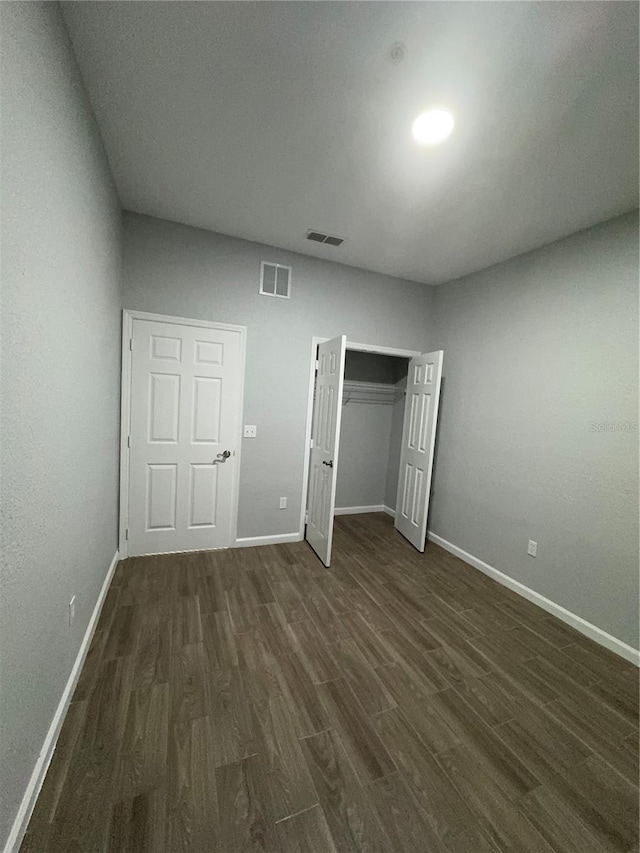 unfurnished bedroom with a closet and dark hardwood / wood-style floors