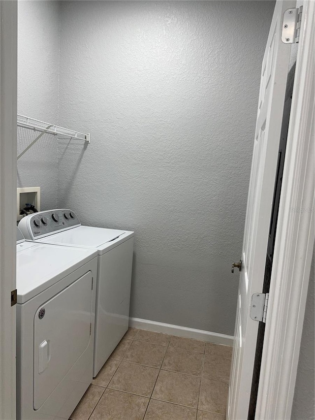 laundry room with washer and clothes dryer and light tile patterned flooring