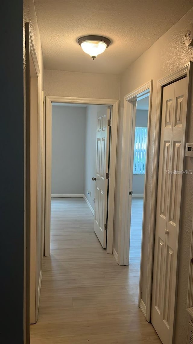 hall featuring light hardwood / wood-style floors and a textured ceiling