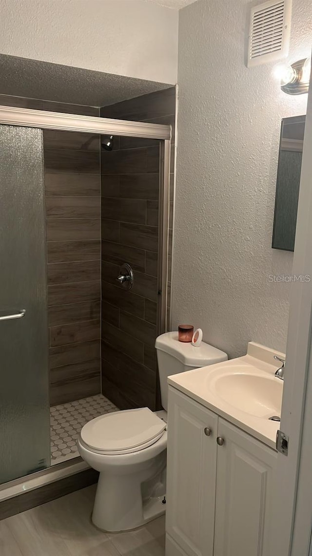 bathroom featuring walk in shower, vanity, toilet, and tile patterned floors