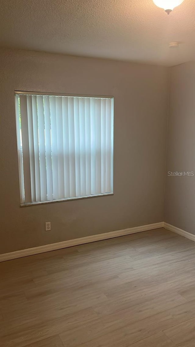 unfurnished room featuring a textured ceiling and light hardwood / wood-style flooring