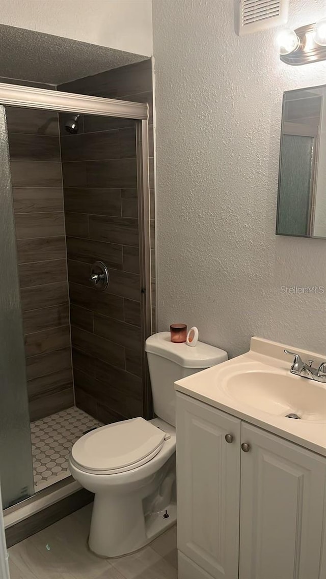 bathroom with vanity, toilet, tile patterned floors, and an enclosed shower