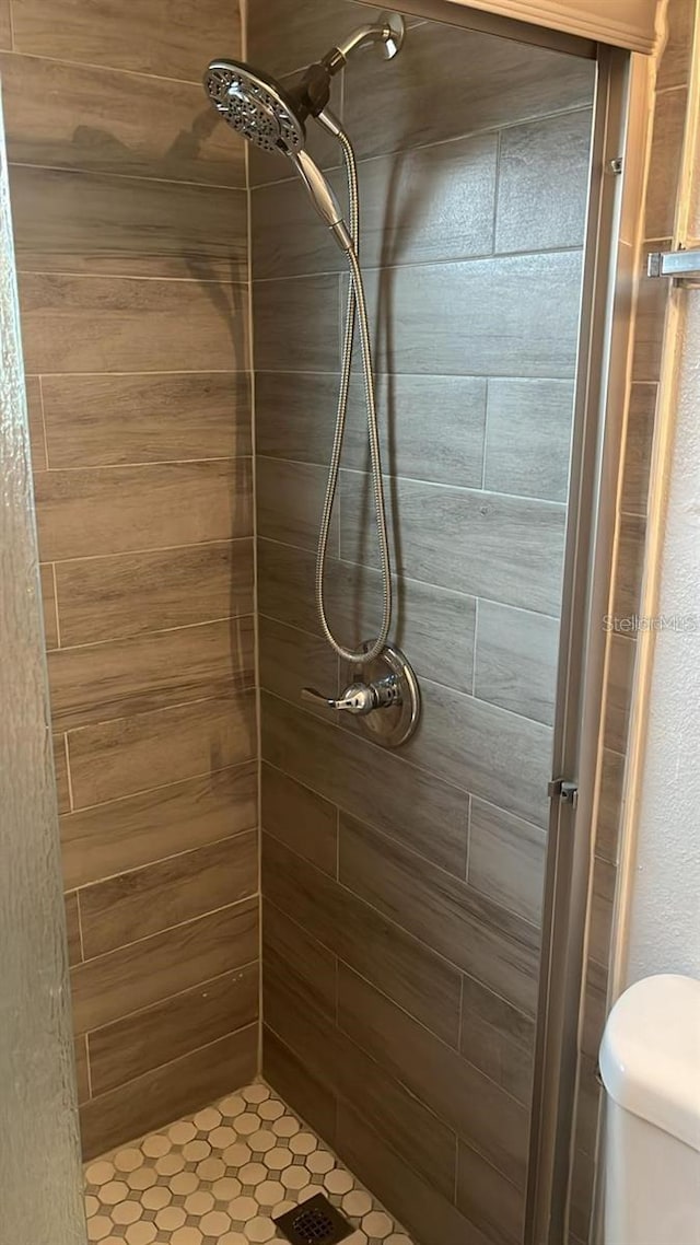 bathroom with a tile shower and toilet