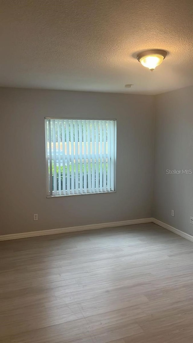 empty room featuring a textured ceiling and light wood-type flooring