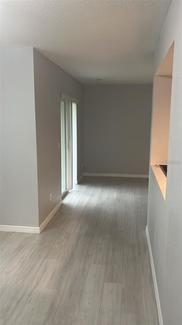 empty room with a textured ceiling and light hardwood / wood-style flooring