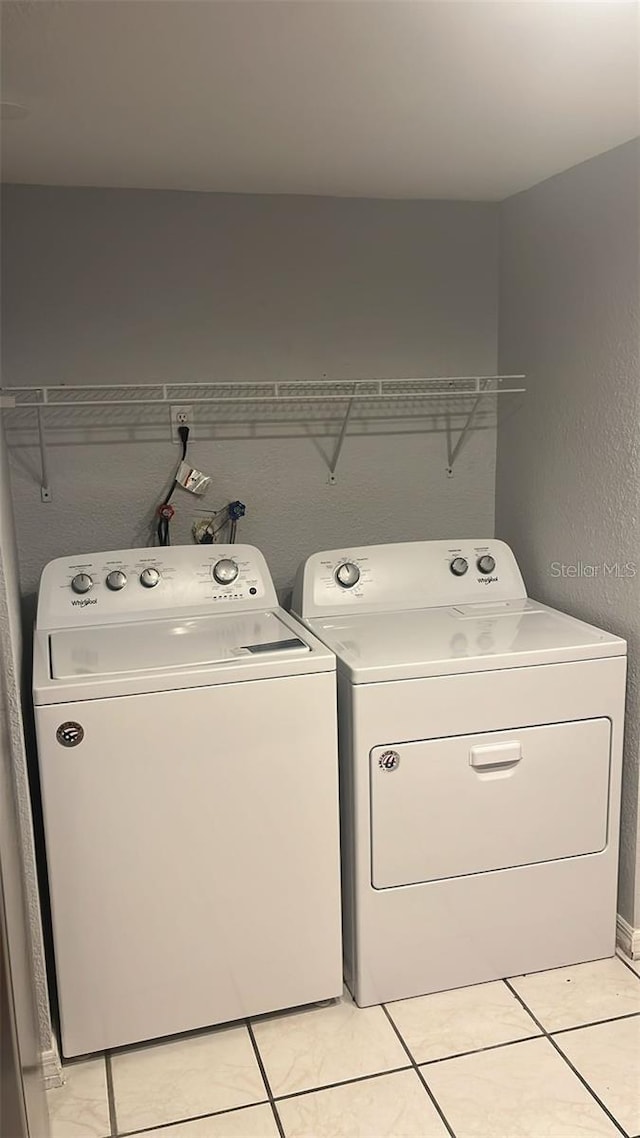 washroom featuring washing machine and clothes dryer and light tile patterned flooring