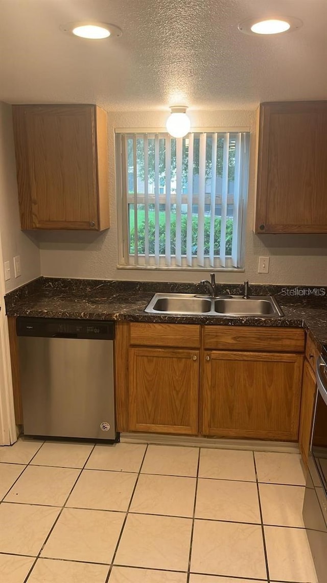 kitchen with a textured ceiling, light tile patterned flooring, sink, and stainless steel appliances