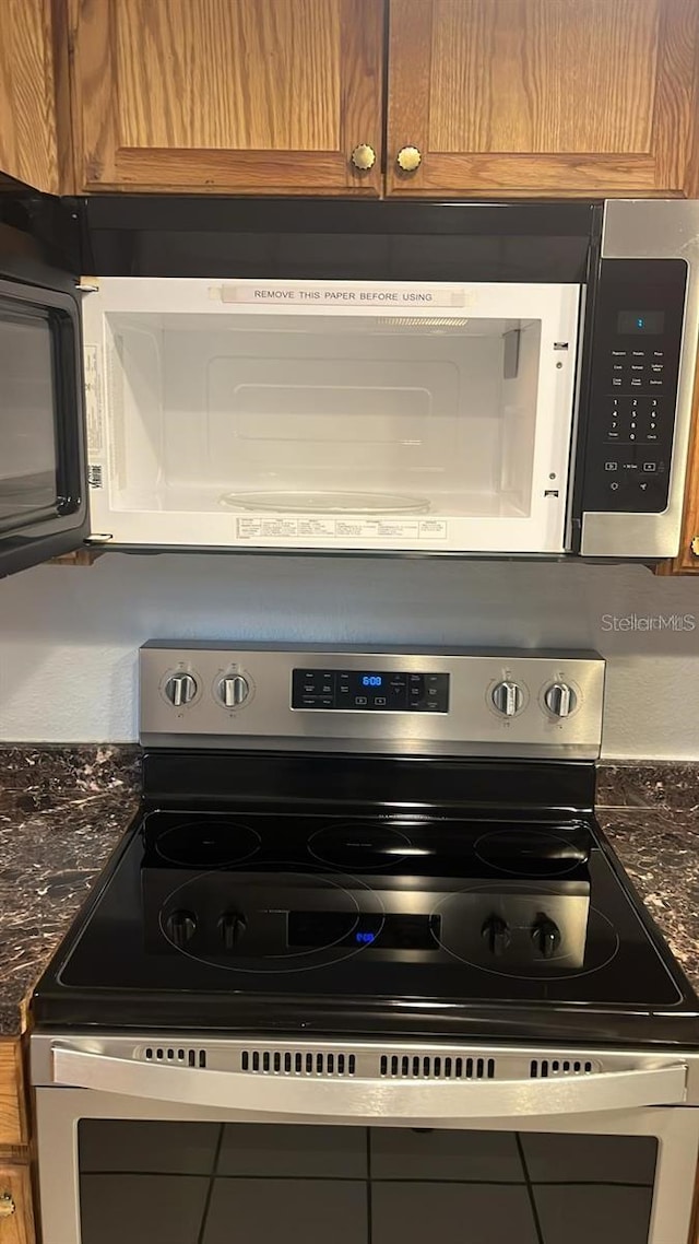 details with dark stone countertops and stainless steel electric range