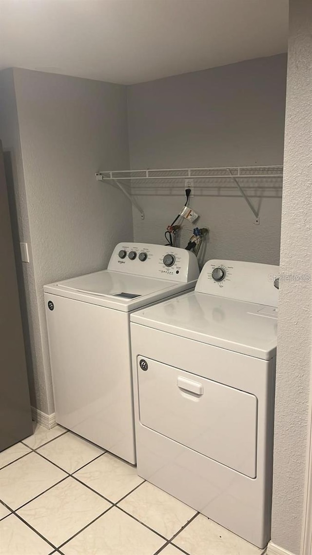 clothes washing area with light tile patterned floors and washing machine and clothes dryer