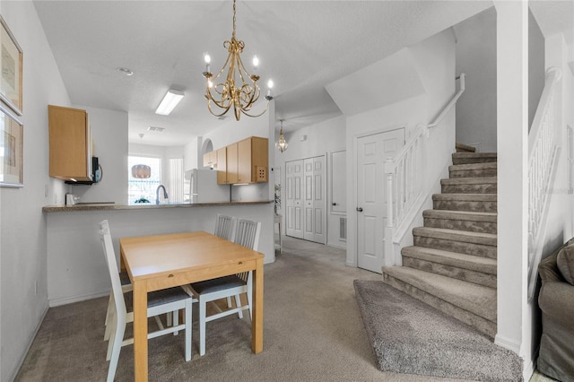 dining area with a notable chandelier, a textured ceiling, light colored carpet, and sink