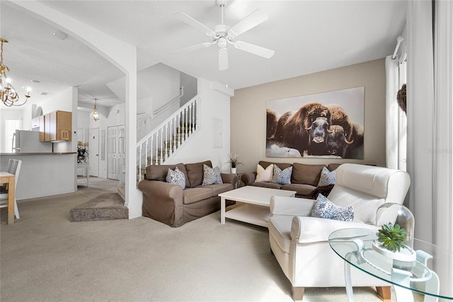 carpeted living room featuring ceiling fan with notable chandelier