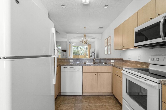 kitchen with an inviting chandelier, white appliances, a textured ceiling, and light brown cabinetry