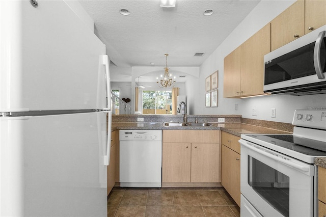 1256 S Beach Cir, Kissimmee, FL 34746 - kitchen with visible vents, white appliances, light brown cabinetry, a sink, and a notable chandelier