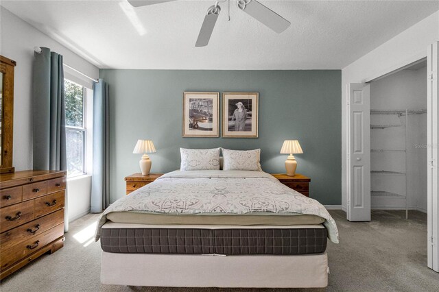 bedroom with a closet, ceiling fan, light colored carpet, and a textured ceiling