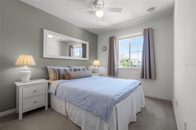 bedroom with ceiling fan, light colored carpet, and a textured ceiling