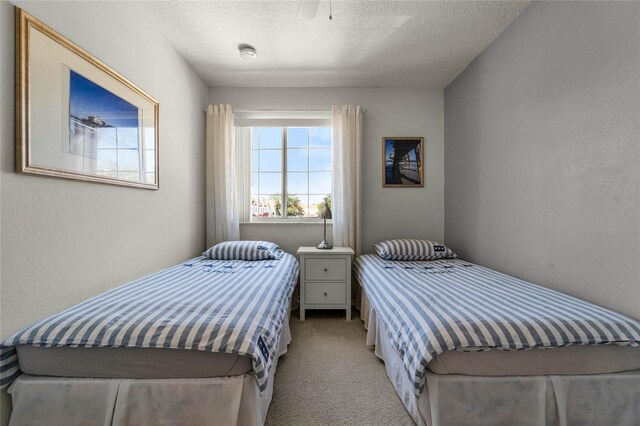 bedroom featuring a textured ceiling, ceiling fan, and light carpet