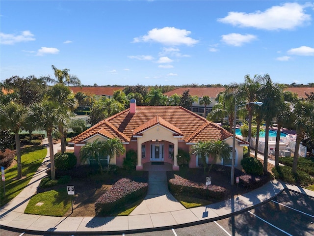 1256 S Beach Cir, Kissimmee, FL 34746 - mediterranean / spanish home featuring a tile roof, stucco siding, and a chimney