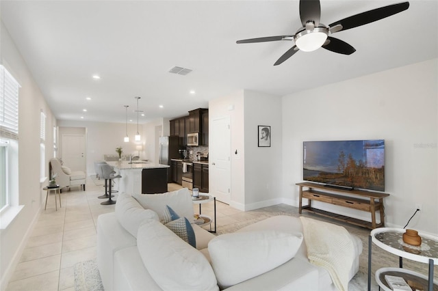 tiled living room with ceiling fan and sink