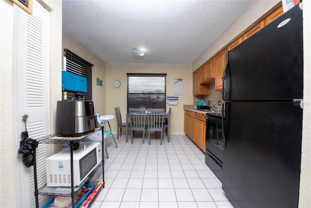 kitchen with black appliances, sink, a textured ceiling, decorative backsplash, and light tile patterned floors