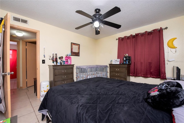 bedroom with a textured ceiling, light tile patterned floors, and ceiling fan