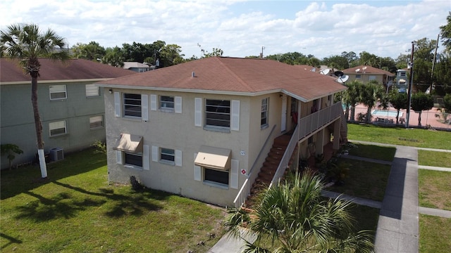 back of house featuring central AC and a lawn