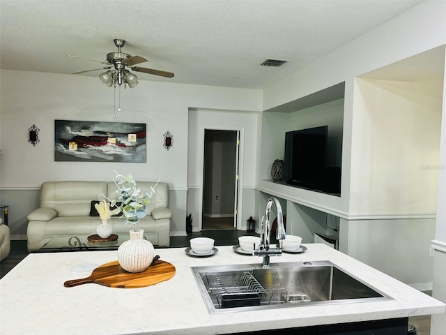 living room with a textured ceiling, ceiling fan, and sink