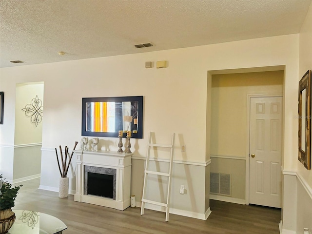 living room with a textured ceiling, a fireplace, and hardwood / wood-style floors