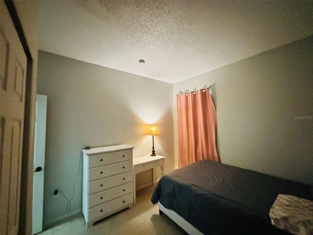 bedroom featuring light carpet and a textured ceiling