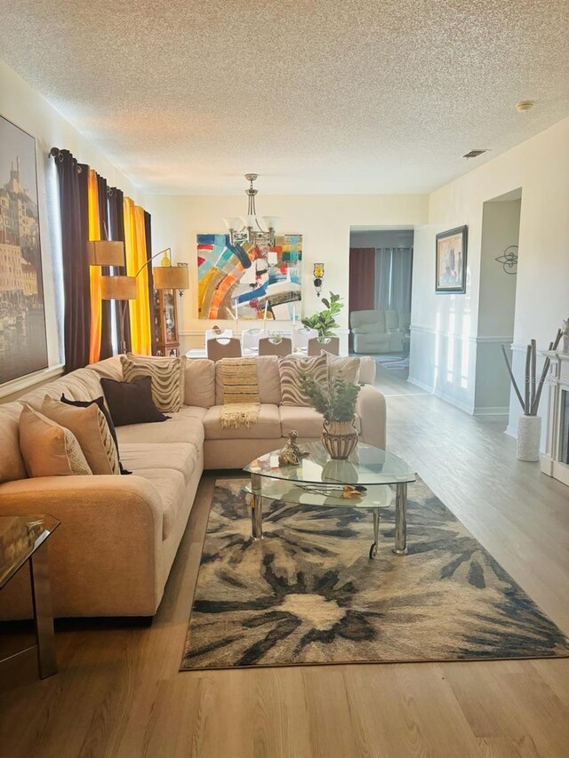 living room featuring a chandelier, a textured ceiling, and hardwood / wood-style floors