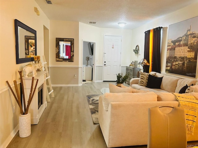 living room featuring light hardwood / wood-style floors and a textured ceiling