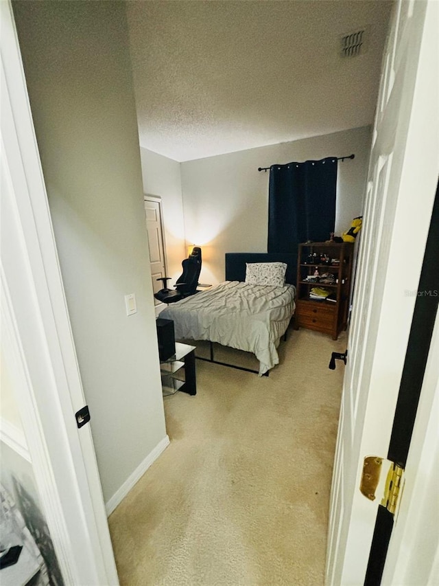 bedroom with light colored carpet and a textured ceiling