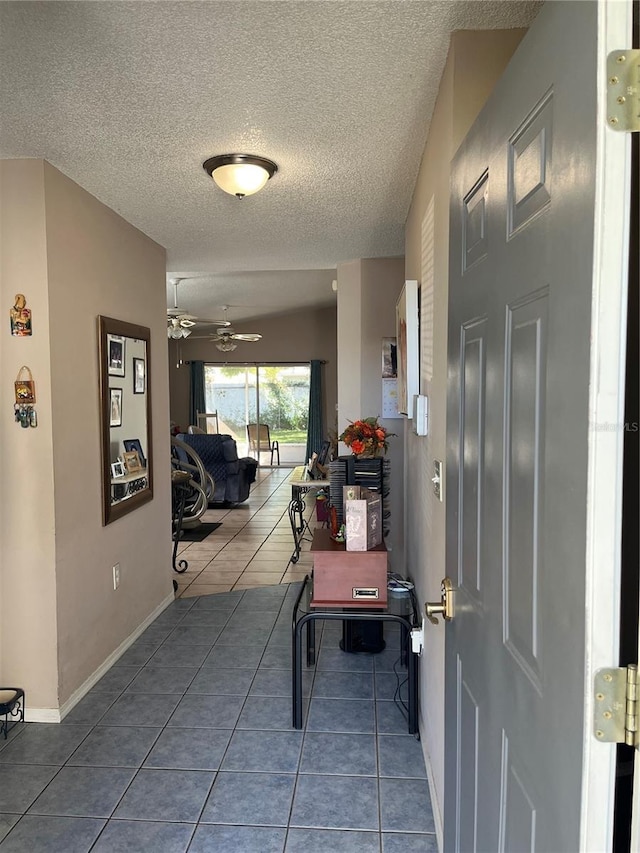 tiled foyer entrance with ceiling fan and a textured ceiling