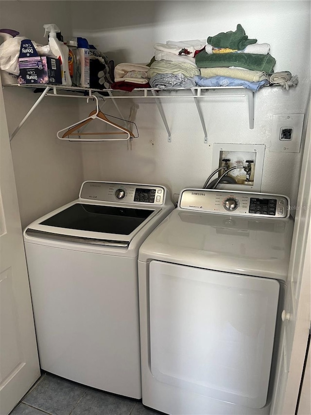 clothes washing area with washer and clothes dryer and tile patterned floors