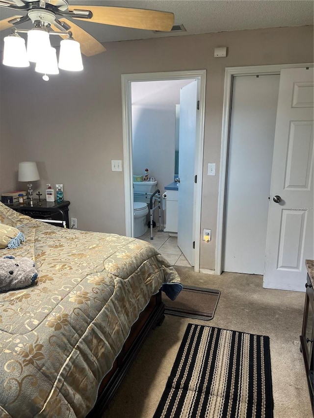 carpeted bedroom with ceiling fan, ensuite bathroom, and a textured ceiling