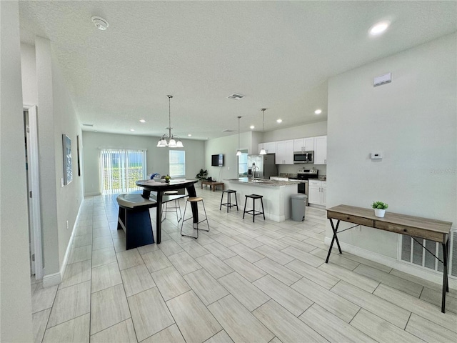 dining room featuring a textured ceiling, sink, a notable chandelier, and light hardwood / wood-style flooring