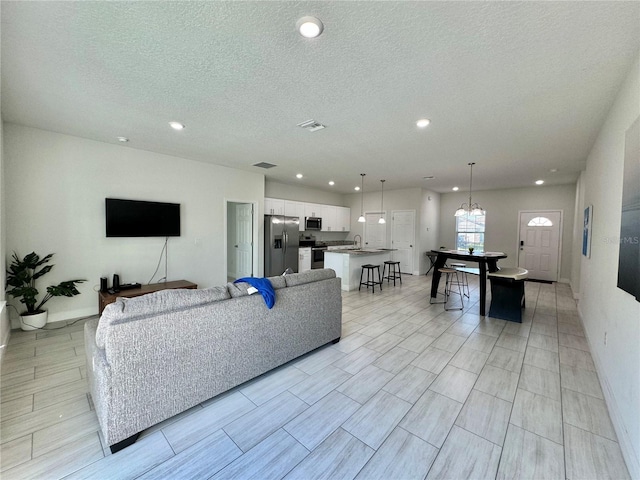 living room with a textured ceiling, a chandelier, and sink