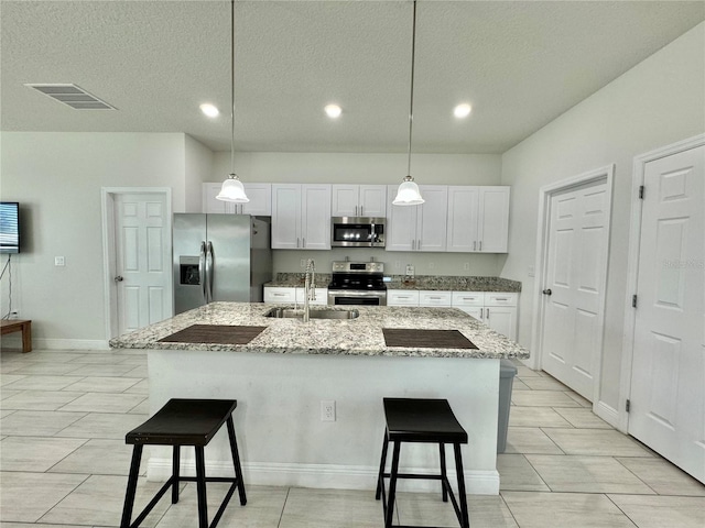 kitchen featuring appliances with stainless steel finishes, sink, white cabinets, a breakfast bar area, and a kitchen island with sink