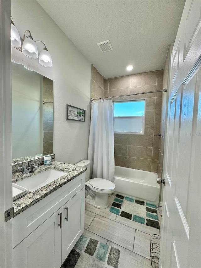 full bathroom featuring shower / tub combo with curtain, vanity, a textured ceiling, and toilet