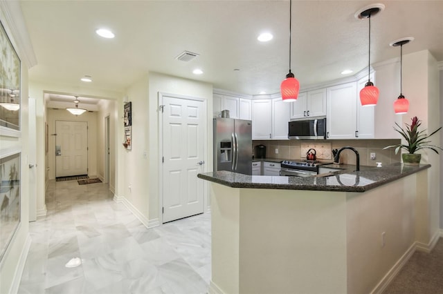 kitchen featuring appliances with stainless steel finishes, hanging light fixtures, kitchen peninsula, and white cabinets