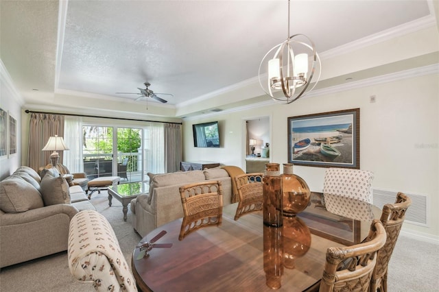 dining area with ceiling fan with notable chandelier, a tray ceiling, ornamental molding, and light colored carpet