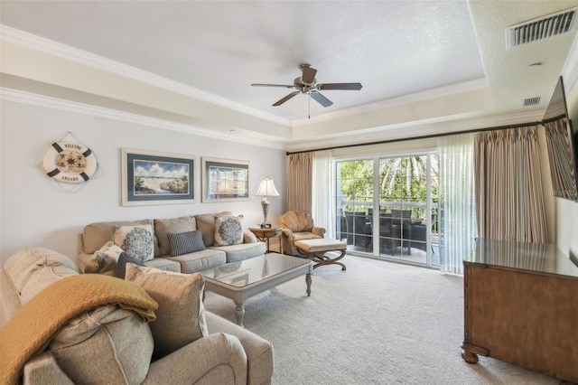 living room with carpet, a tray ceiling, ceiling fan, and ornamental molding