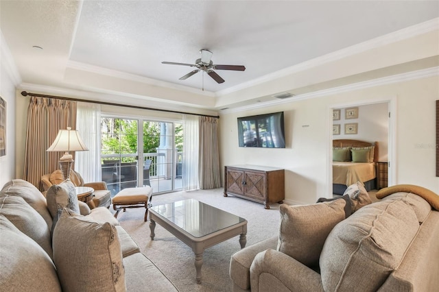 carpeted living room featuring ornamental molding, a tray ceiling, and ceiling fan